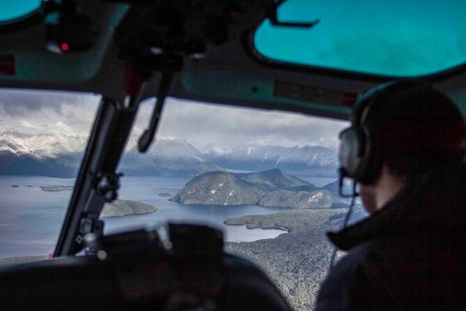 The view past a pilot's headset over wooded islands and a wide lake