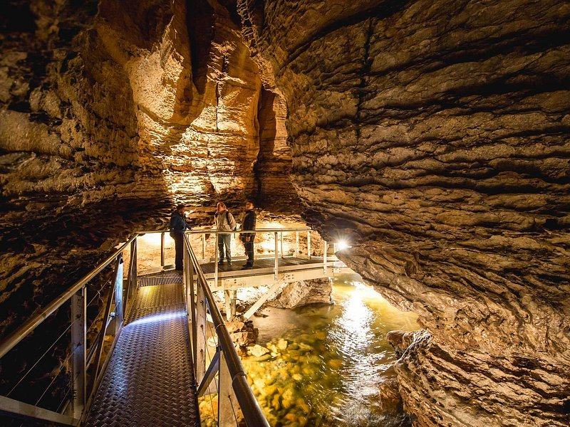 A lit walkway above an underground stream in a limestone cave