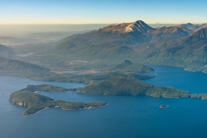 Wooded islands scattered across a wide blue lake, seen from the air